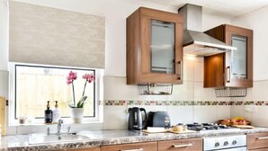 Una cocina moderna con armarios de madera, estufa a gas y una ventana llena de flores.