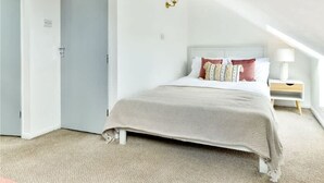 Un dormitorio con una cama, una mesita de noche y un radiador.
