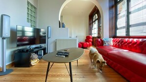 Ein modernes Wohnzimmer mit einem roten Sofa, einem Fernseher und einem Hund.