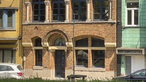 Ein mehrstöckiges Gebäude mit Ziegelverkleidung, großen Bogenfenstern und einem symmetrischen Design.