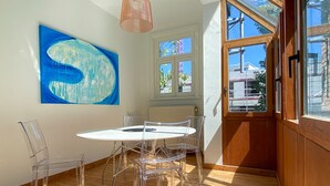 Ein Zimmer mit einem runden Tisch und Stühlen, einem großen abstrakten Gemälde und Blick durch ein Fenster.
