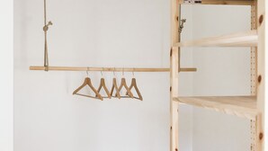 Une pièce comprenant un banc en bois, un portant à vêtements et une étagère en bois.