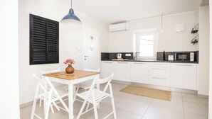 A modern kitchen with white cabinets, a wooden dining table, and a blue pendant light. - Riba apartment, 2 bedrooms, terrace, airco, 54 m2 (Tolmin)