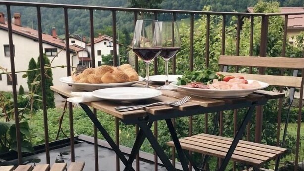 A balcony with a table set for a meal, including bread and a glass of red wine, overlooking a mountainous landscape. - Riba apartment, 2 bedrooms, terrace, airco, 54 m2 (Tolmin)