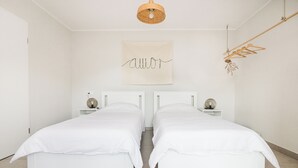 A bedroom with two single beds, a hanging light fixture, a wall-mounted artwork, and a wooden hanger rack. - Riba apartment, 2 bedrooms, terrace, airco, 54 m2 (Tolmin)