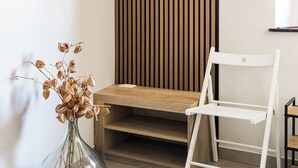 A room with a wooden slat wall, a white chair, a small wooden table, and a clear glass vase with dried flowers. - Riba apartment, 2 bedrooms, terrace, airco, 54 m2 (Tolmin)