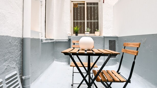 A small outdoor seating area with a wooden table and chairs, a potted plant, and a window with a view. - M (RVI40) Cozy one-bedroom apartment in Cuatro Caminos (Madrid)