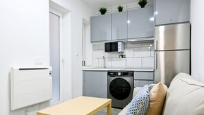 A compact kitchen with a washing machine, a microwave, and a refrigerator. - M (RVI40) Cozy one-bedroom apartment in Cuatro Caminos (Madrid)