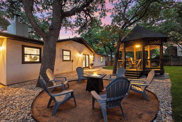 Eine Terrasse mit Adirondack-Stühlen, einer Feuerstelle und einem Gazebo.