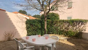 A white table with four chairs in a garden setting.