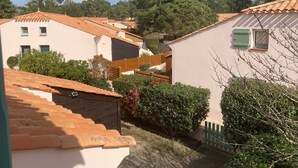 A residential area with terracotta-tiled roofs, wooden fences, and lush greenery.