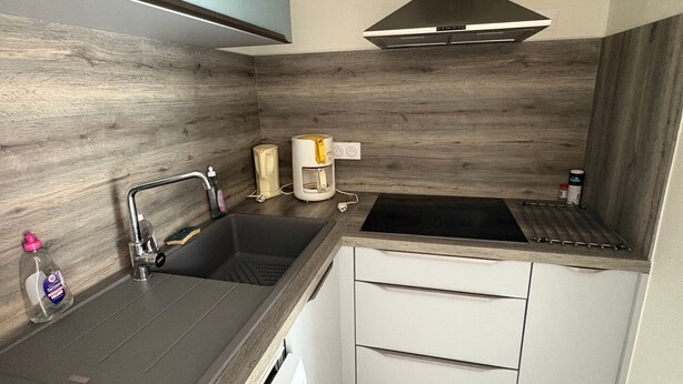 A compact kitchen with a sink, a coffee maker, and a stove.