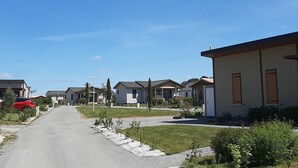 A residential street with houses, a red car parked on the side, and a clear blue sky.