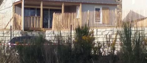 Un edificio residencial con techo inclinado, cerca de madera y pared de piedra.