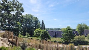 Ein von einer Hecke umgebener Gartenbereich mit Bäumen und blauem Himmel.