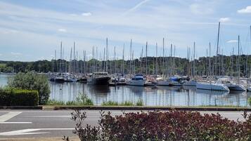 A marina with multiple boats docked, a bridge, and a view of a hilly landscape.