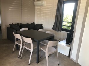 Un interno moderno con un tavolo da pranzo, sedie bianche, un divano grigio e una TV.