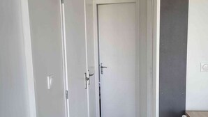 A hallway with white doors, a wooden floor, and a small table with a chair.