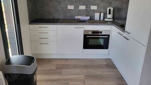 A modern kitchen with white cabinets, a built-in oven, and a coffee maker.