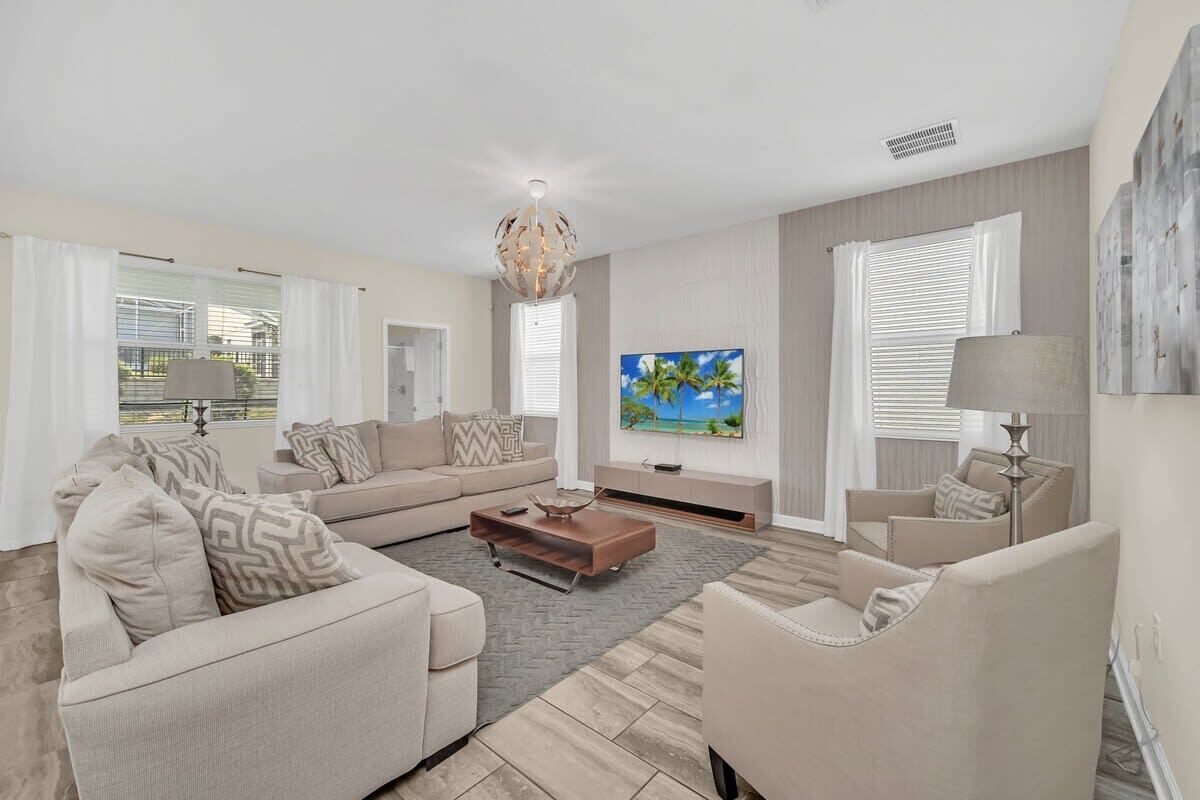 A modern living room with a sofa set, a coffee table, a TV, and a painting on the wall.