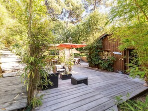 Eine Holzterrasse mit Sitzgelegenheiten und einem roten Sonnenschirm.