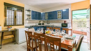 A compact kitchen with blue cabinets, a dining table set for four, and a small island with a microwave. - Beautiful home in Alcala la Real (Alcala la Real)