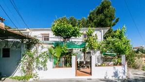 A two-story house with a patio, a green umbrella, and a tree. - Beautiful home in Alcala la Real (Alcala la Real)