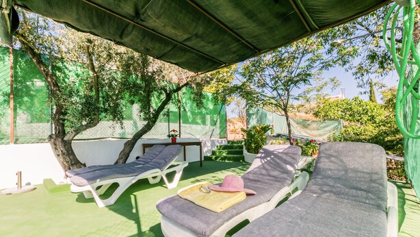 A covered outdoor seating area with two lounge chairs and a table, surrounded by greenery and a fence. - Beautiful home in Alcala la Real (Alcala la Real)
