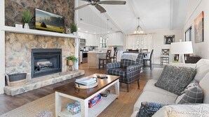 Un salón amplio con chimenea, una zona de comedor y una cocina al fondo.