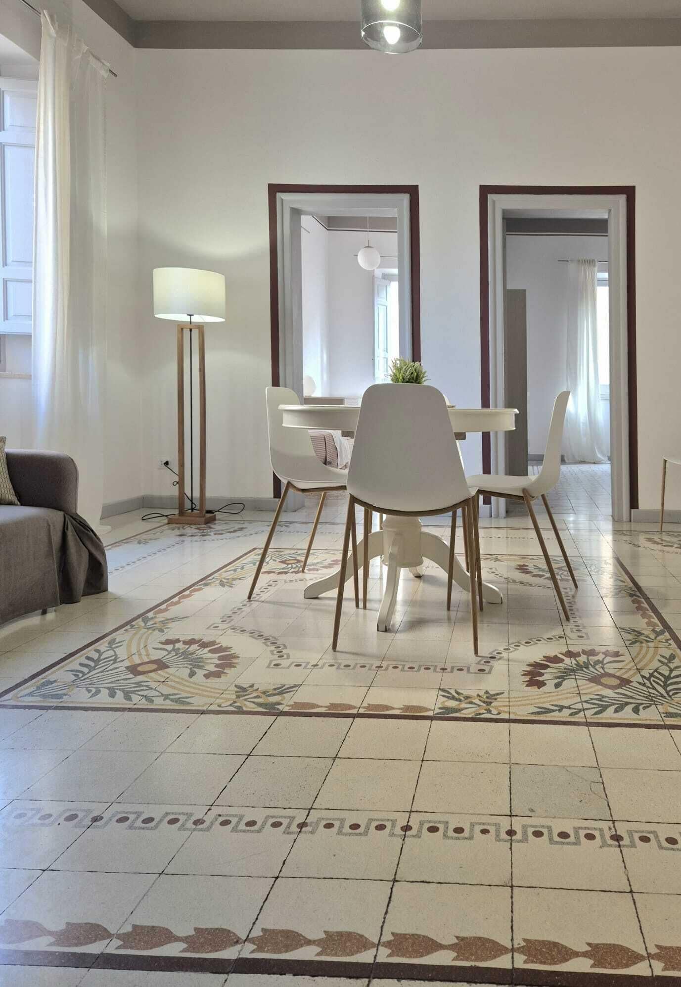 A modern living room with a dining area, a sofa, a floor lamp, and a patterned rug.