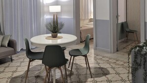A dining area with a round table, four chairs, a lamp, and a plant. - CASE VACANZE LA MATTANZA (Trapani)