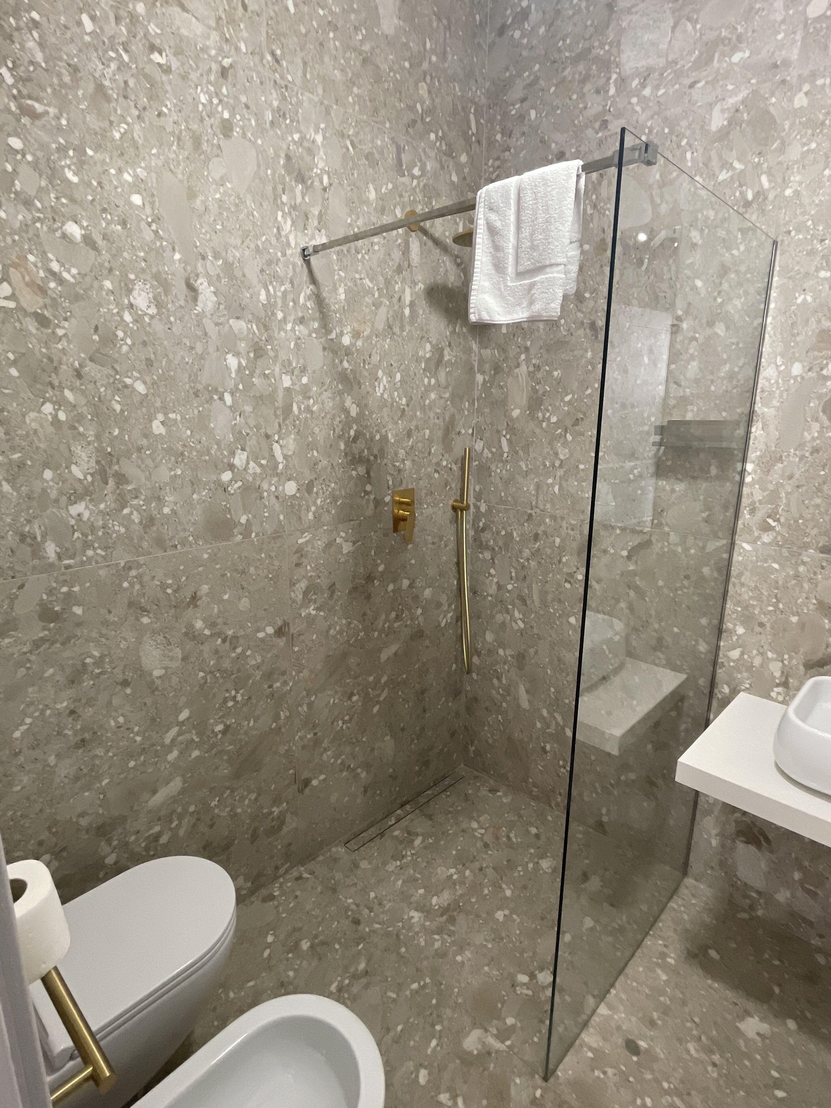 A modern bathroom with a glass-enclosed shower, a toilet, and a sink with a white countertop.
