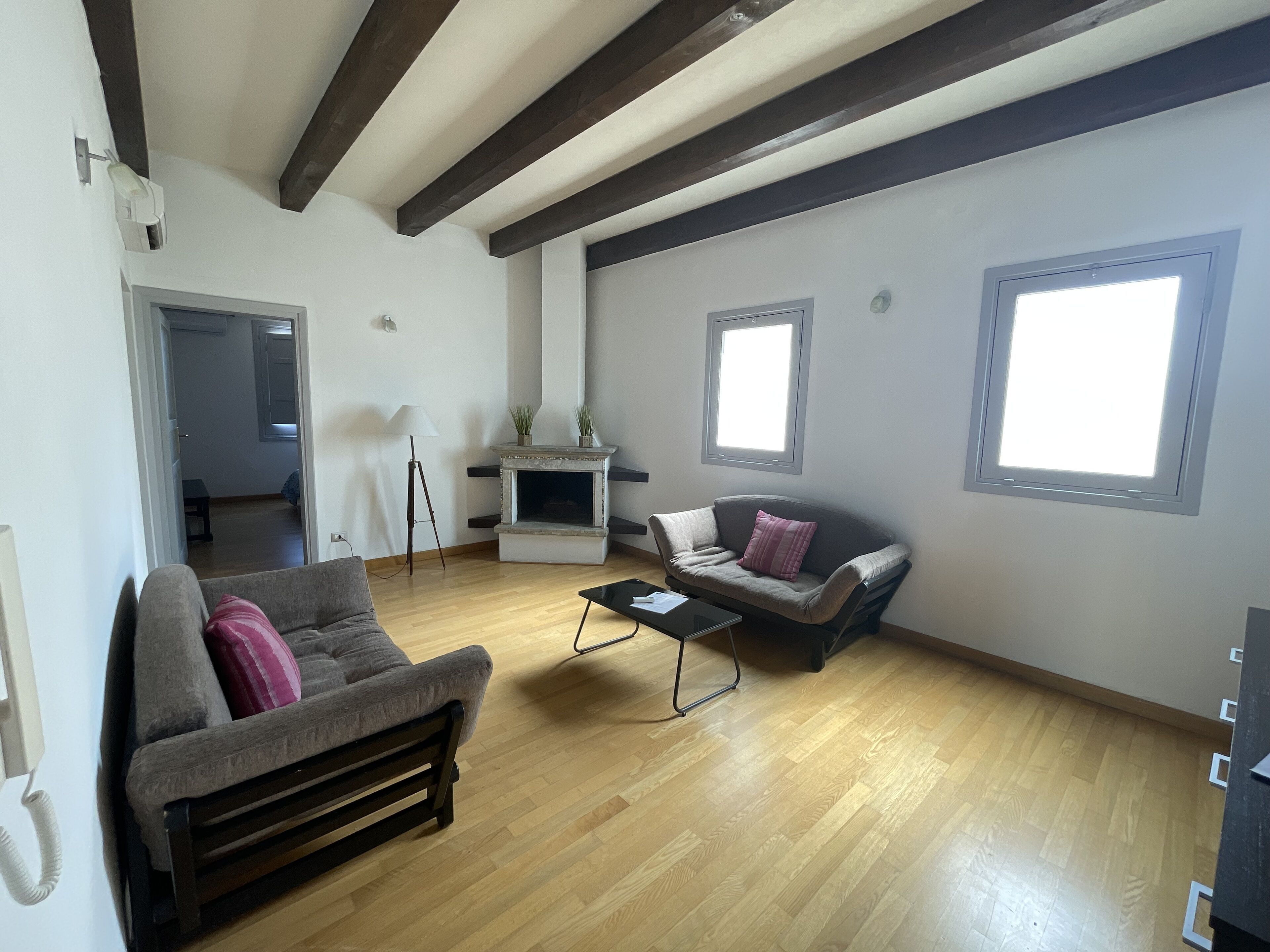 A spacious living room with a fireplace, two sofas, a coffee table, and wooden flooring.