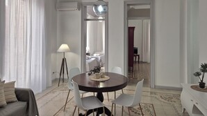 A dining area with a round table, chairs, a lamp, and a potted plant. - CASE VACANZE LA MATTANZA (Trapani)