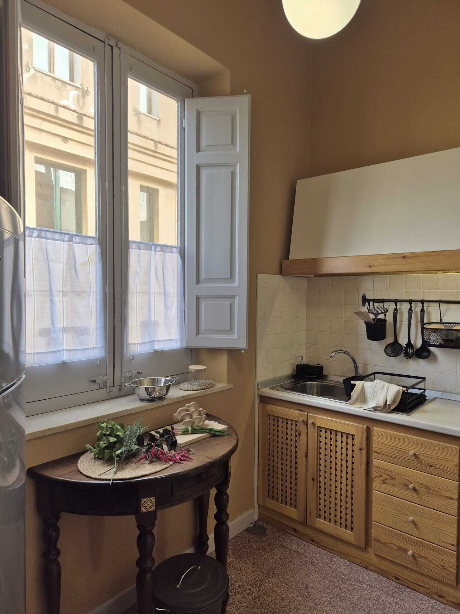Eine kleine Küche mit Fenster, Spüle und Holzschränken.