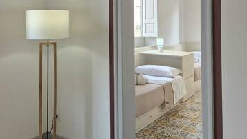 Un pasillo que conduce a un dormitorio con una cama, una mesita de noche y una lámpara.