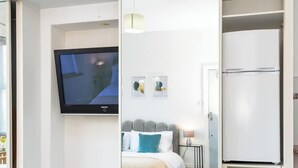 A hotel room with a bed, a television, and a refrigerator.
