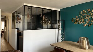Une cuisine moderne aux couleurs noir et blanc, un coin repas avec une table et des chaises en bois, et un mur d’accent de couleur turquoise orné d’une décoration en forme de papillon.