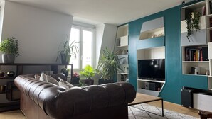 Un salon moderne avec un canapé en cuir, un téléviseur à écran plat et un mur d’accent de couleur turquoise.