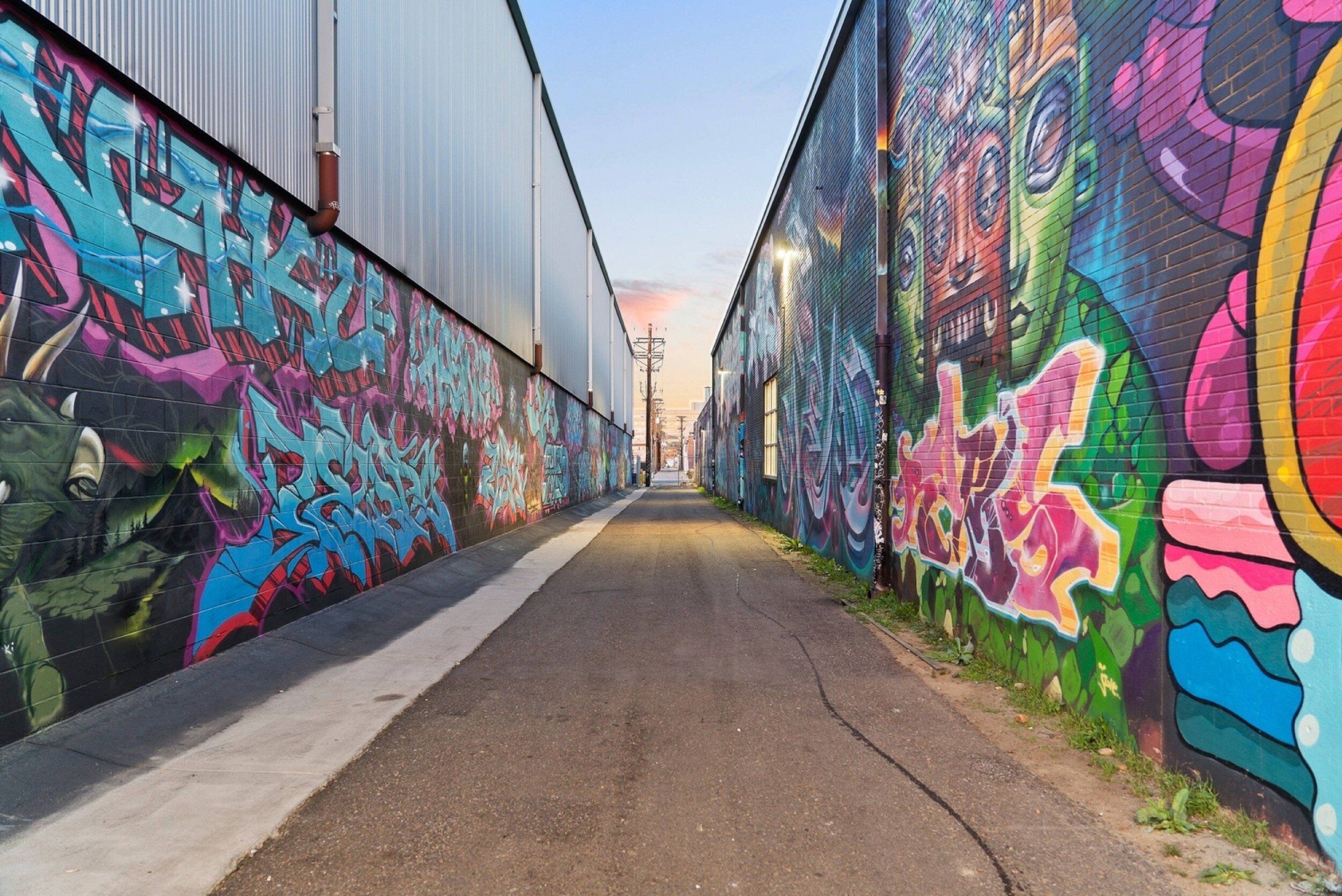 A narrow alleyway with colorful graffiti on the walls.