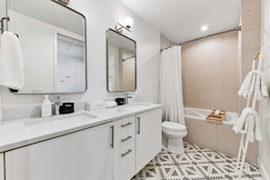 A modern bathroom with a white sink, two mirrors, a toilet, and a shower area. - Dog-Friendly 2BR Boho Loft in RiNo | Walk to Mission Ballroom & Breweries (Denver)