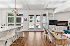 A modern kitchen with a white countertop, bar stools, and a hanging light fixture. - Dog-Friendly 2BR Boho Loft in RiNo | Walk to Mission Ballroom & Breweries (Denver)