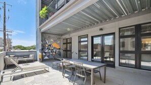 Une terrasse sur le toit avec une table et des chaises, un canapé et un mur décoratif.