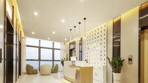 A modern reception area with a reception desk, seating, and a large window offering a view. - QianYue Hotel (Wuzhou)