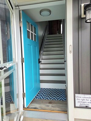 Eine Treppe mit einer blauen Tür, die zu einer Zwischenebene führt.