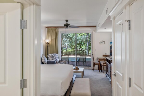 A hotel room with a bed, a desk, a chair, and a view of the outdoors.