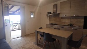 Et kompakt køkken med spiseplads, et lille vindue og en balkon.