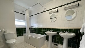 Un baño moderno con bañera, dos lavamanos, inodoro y ducha.