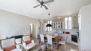 A spacious living room with a dining area, kitchen, and a ceiling fan.