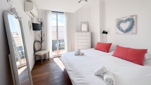 A bedroom with a large bed, a dresser, a mirror, a TV, and a heart-shaped decoration on the wall.